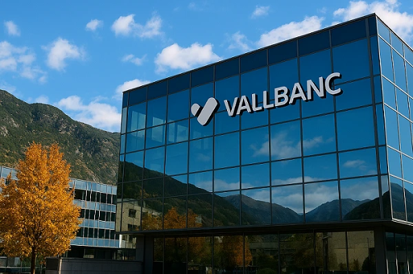 J.C. Flowers: Vallbanc building with logo prominently displayed, reflecting mountains and blue sky, autumn tree in foreground.