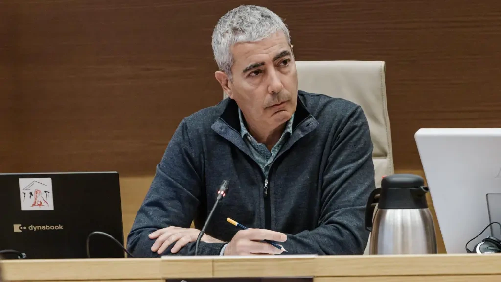 joan pau miquel prats, looking thoughtful at a desk with a laptop and coffee carafe.